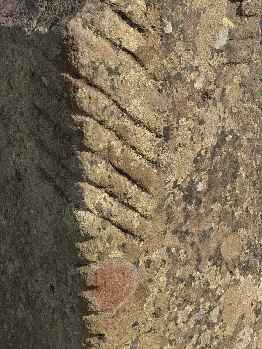 Close up of a standing stone with a row of slanting strokes cut over its corner